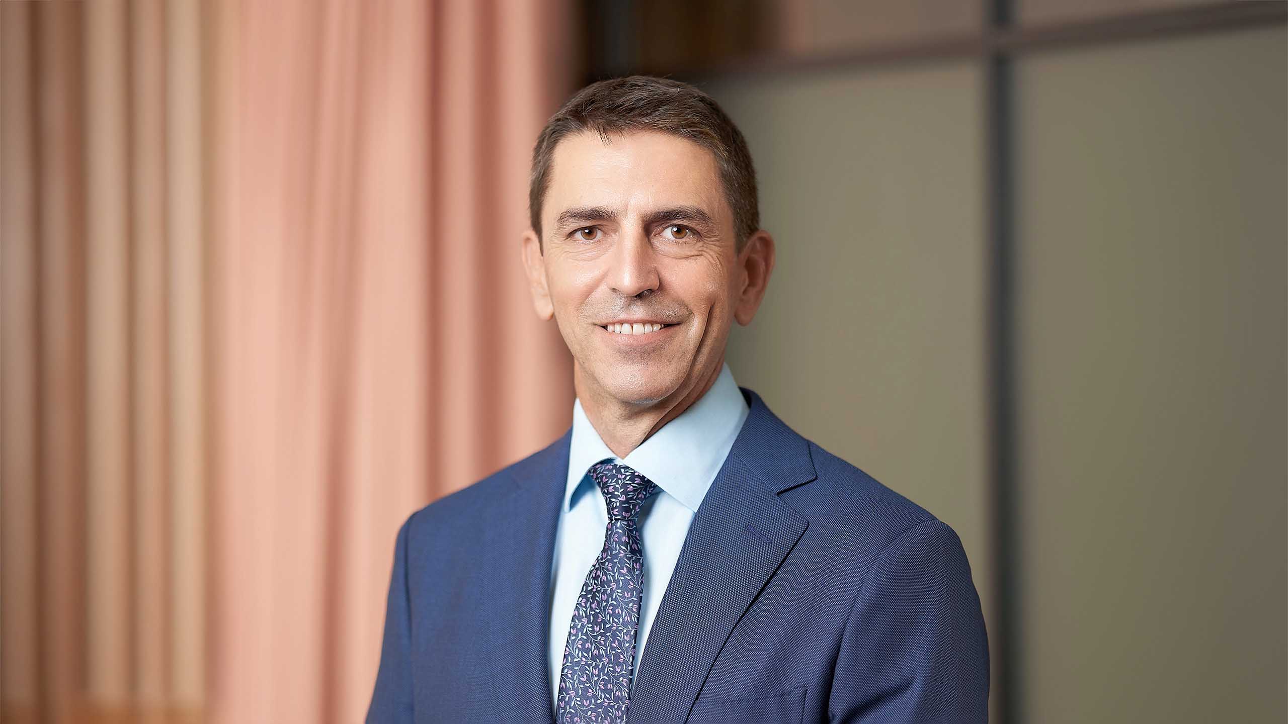 corporate headshot of a man in an office